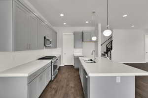 Kitchen with gray cabinetry, appliances with stainless steel finishes, recessed lighting, backsplash, and dark wood finished floors