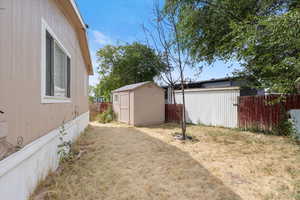 Fenced backyard featuring a storage unit