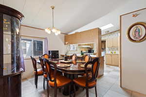 Dining space featuring a chandelier, vaulted ceiling, and light tile patterned floors