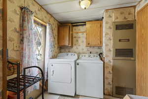 Laundry area with wallpapered walls, separate washer and dryer, a heating unit, and cabinet space