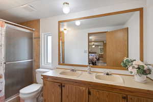 Ensuite bathroom featuring double vanity and a shower with door