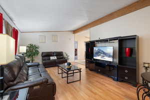 Living area with light wood finished floors and beamed ceiling