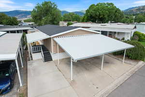 View of front of house with a mountain view, concrete driveway, and a metal roof carport.