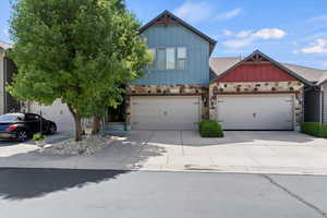 View of front of property featuring board and batten siding, stone siding, and concrete driveway