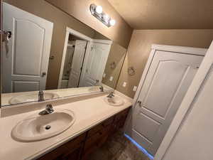 Bathroom featuring double vanity and a textured ceiling