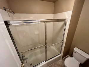 Bathroom with toilet and shower / bath combination with glass door