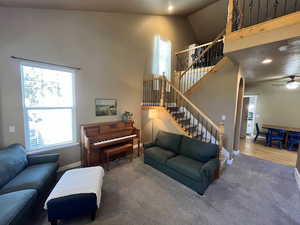 Living area featuring carpet flooring, a ceiling fan, arched walkways, stairs, and vaulted ceiling