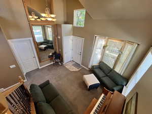 Living room featuring high vaulted ceiling, carpet flooring, and a chandelier