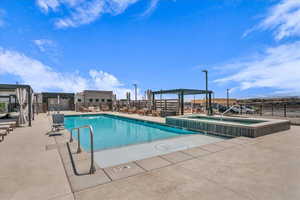 Community pool with a hot tub, a pergola, and a patio area