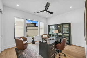 Office with light wood-style floors, ceiling fan, and recessed lighting