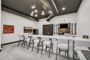 Kitchen featuring glass insert cabinets, a breakfast bar area, dark speckled floor, a chandelier, and beverage cooler