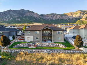 Back of house featuring a balcony, a patio area, a mountain view, a fenced backyard, and stucco siding