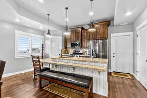 Second kitchen with stainless steel appliances, a kitchen bar, recessed lighting, a center island with sink, and dark wood-type flooring