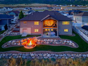 Back of house with an outdoor fire pit, a balcony, stucco siding, a patio area, and a fenced backyard
