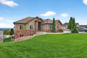 View of front of house with a front yard, roof with shingles, stone siding, and board and batten siding
