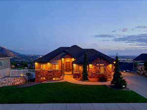 View of front of home featuring stone siding and a lawn