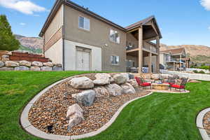 Rear view of house featuring a balcony, a patio area, a lawn, a mountain view, and stucco siding