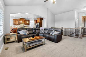 Living room featuring arched walkways, light carpet, ceiling fan, and high vaulted ceiling