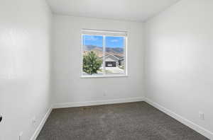 Unfurnished room featuring dark colored carpet and baseboards