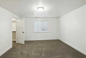 Unfurnished bedroom featuring a textured ceiling and dark carpet