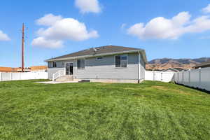 Back of house with a fenced backyard, a mountain view, a gate, entry steps, and a shingled roof