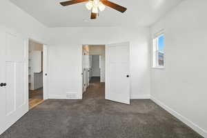 Unfurnished bedroom with dark colored carpet and a ceiling fan