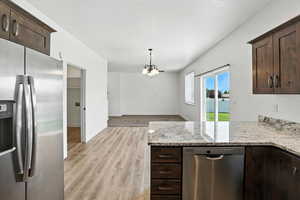 Kitchen featuring appliances with stainless steel finishes, dark brown cabinetry, a chandelier, and light wood-type flooring