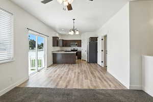 Kitchen with dark brown cabinetry, ceiling fan, open floor plan, light countertops, and appliances with stainless steel finishes