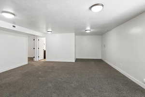 Finished below grade area with dark carpet and a textured ceiling