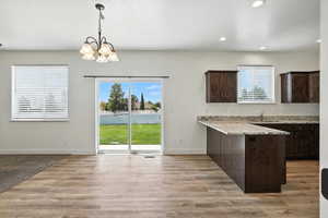 Kitchen featuring dark brown cabinets, a peninsula, recessed lighting, a chandelier, and pendant lighting