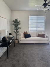Living area with carpet floors, ceiling fan, and a textured ceiling