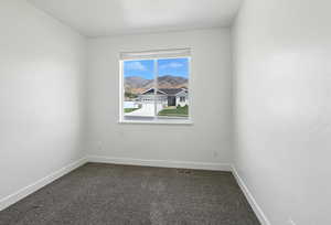 Empty room featuring dark carpet and baseboards