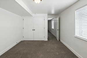 Unfurnished bedroom featuring dark carpet and a closet