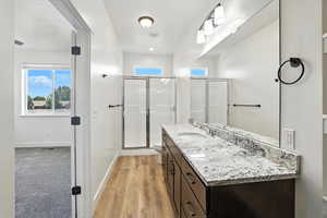 Bathroom featuring a stall shower, vanity, and wood finished floors