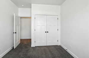 Unfurnished bedroom with dark carpet and a closet