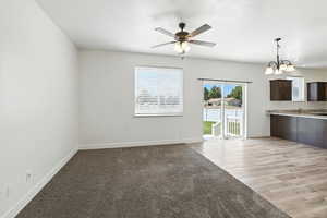 Unfurnished living room with a chandelier, a ceiling fan, and light wood finished floors