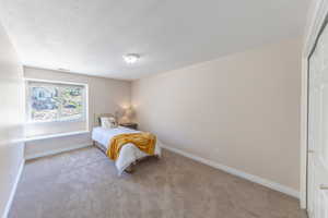 Carpeted bedroom with a textured ceiling and baseboards