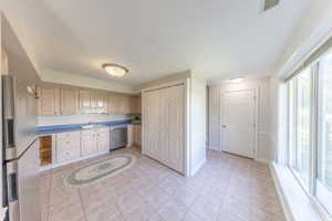 Kitchen featuring stainless steel appliances, light tile patterned floors, and cream cabinetry