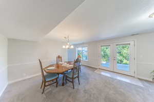 Carpeted dining area featuring a chandelier and french doors