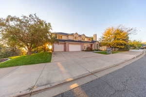 Traditional-style home featuring a garage, driveway, stucco siding, and a chimney