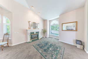 Living area featuring carpet floors, plenty of natural light, vaulted ceiling, and a tile fireplace