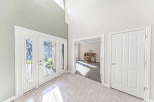 Foyer entrance featuring light tile patterned floors, french doors, and a high ceiling