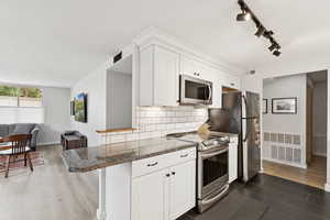 Open Kitchen featuring stainless steel appliances, stone counters, backsplash, and white cabinetry