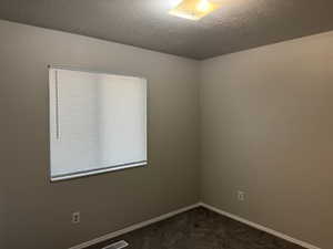 Bedroom featuring a textured ceiling and dark carpet