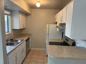 Kitchen with under cabinet range hood, light countertops, white cabinetry, and dishwasher