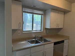 Kitchen with white cabinetry, dishwasher, and light countertops