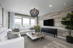 Living room with wood walls, recessed lighting, a chandelier, wood finished floors, and a textured ceiling