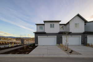 View of front facade with a garage, concrete driveway, a mountain view, board and batten siding, and brick siding