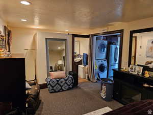 Carpeted bedroom featuring estacked washer and dryer, freestanding refrigerator, a textured ceiling, recessed lighting, and a fireplace