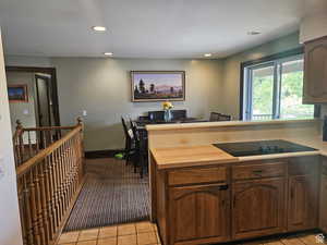 Kitchen featuring black electric cooktop, recessed lighting, a peninsula, light tile patterned floors, and wooden counters